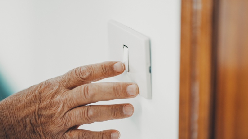 Mano persona anziana accende interruttore luce